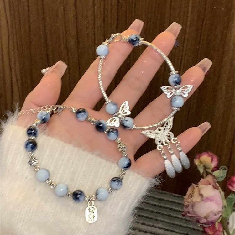 Vòng tay sứ xanh trắng phong cách cổ điển, có đính cườm và tua rua dạng cánh bướm, phù hợp đeo mỗi ngày