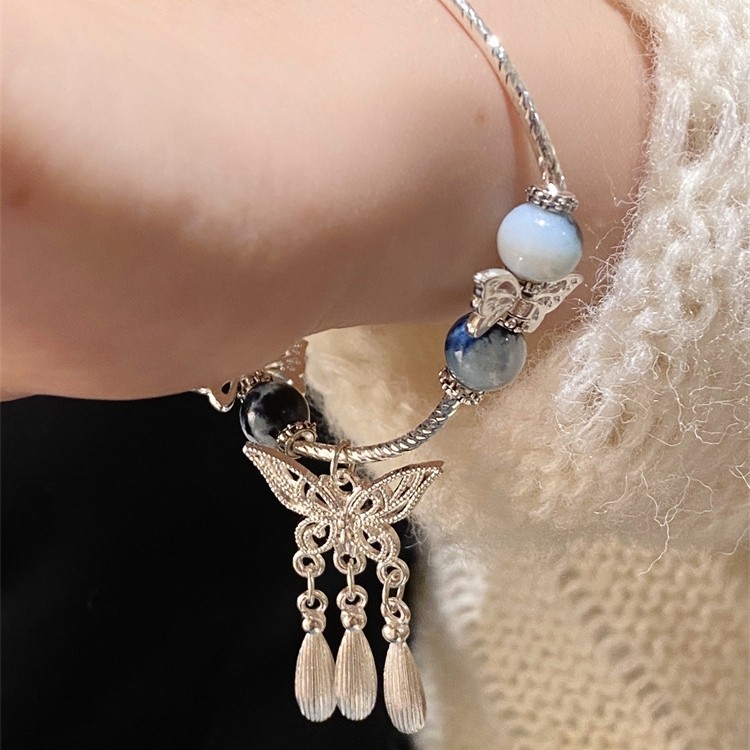 Vòng tay sứ xanh trắng phong cách cổ điển, có đính cườm và tua rua dạng cánh bướm, phù hợp đeo mỗi ngày