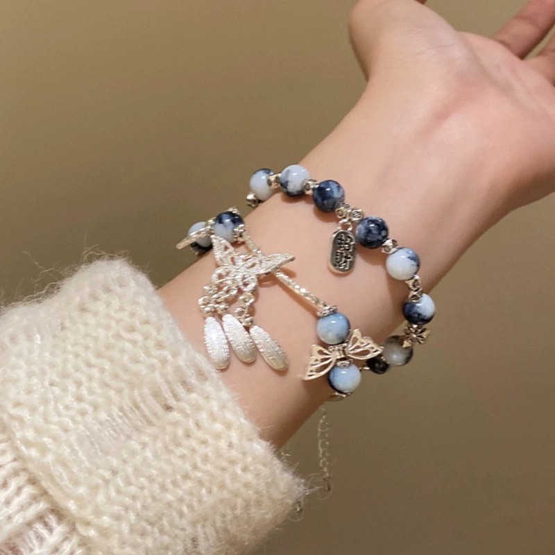 Vòng tay sứ xanh trắng phong cách cổ điển, có đính cườm và tua rua dạng cánh bướm, phù hợp đeo mỗi ngày