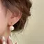 Bông tai màu vàng với ngọc trai và họa tiết hoa xoắn ốc, phù hợp phong cách thời trang cá tính và cổ điển.