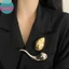 Sản phẩm phụ kiện thời trang kim loại bóng với thiết kế hình học giọt nước và thổ cẩm, phù hợp cho các nàng dự tiệc hoặc làm corsage, quà tặng tinh tế.