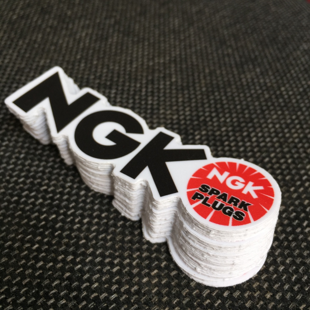 NGK[8.5X2.4cm] decal cao cấp chống nước, sắc nét, bền màu, dính chặt. Hình dán logo trang trí mọi nơi, in theo yêu cầu