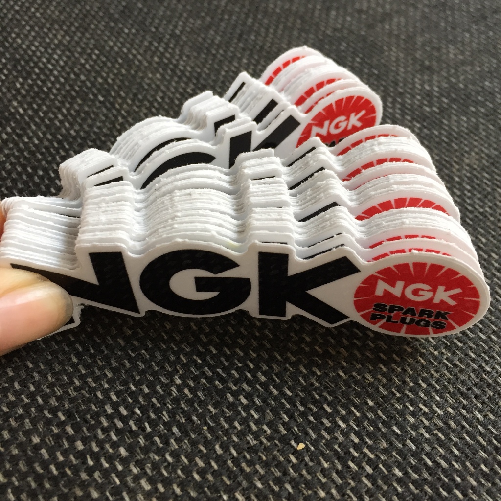 NGK[8.5X2.4cm] decal cao cấp chống nước, sắc nét, bền màu, dính chặt. Hình dán logo trang trí mọi nơi, in theo yêu cầu