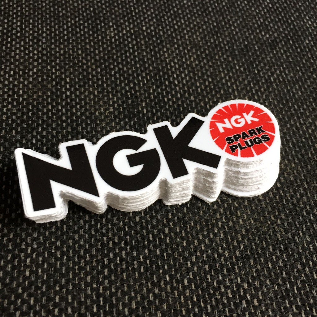 NGK[8.5X2.4cm] decal cao cấp chống nước, sắc nét, bền màu, dính chặt. Hình dán logo trang trí mọi nơi, in theo yêu cầu