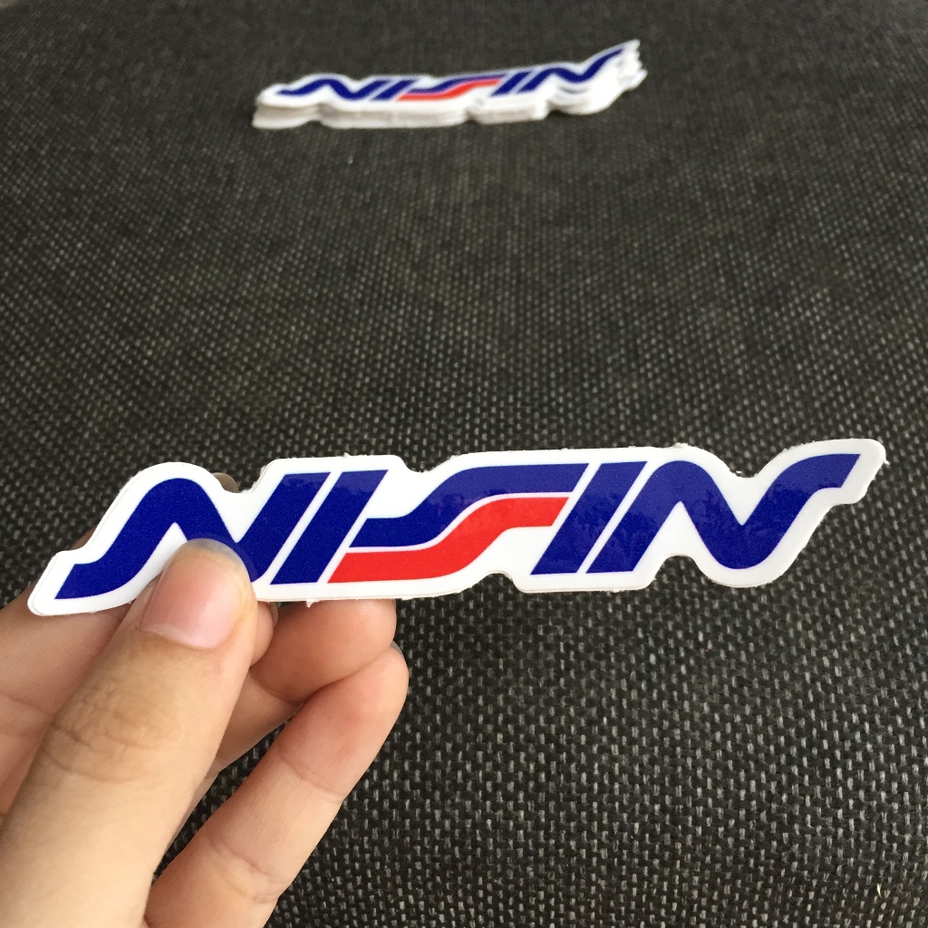 NISSIN[11.2x2cm] decal cao cấp chống nước, sắc nét, bền màu, dính chặt. Hình dán logo trang trí mọi nơi, in theo yêu cầu