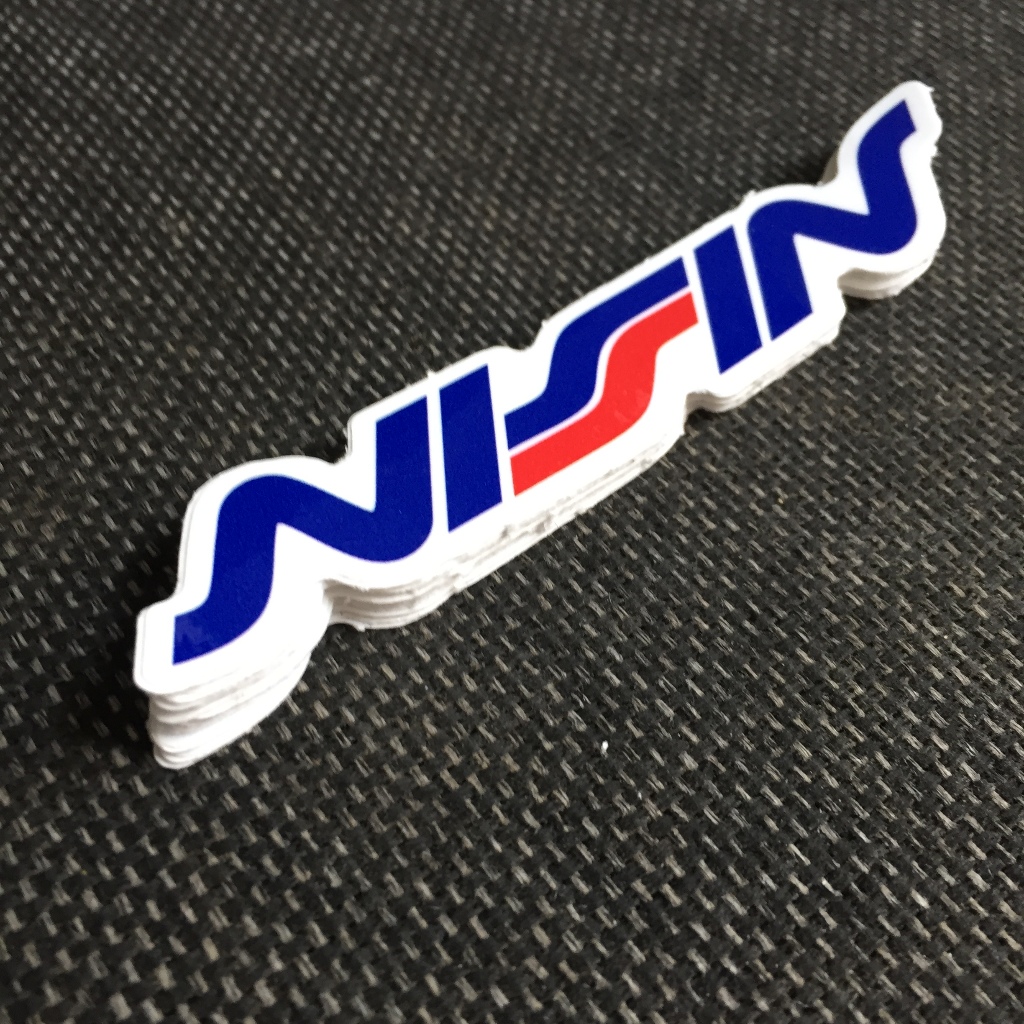 NISSIN[11.2x2cm] decal cao cấp chống nước, sắc nét, bền màu, dính chặt. Hình dán logo trang trí mọi nơi, in theo yêu cầu