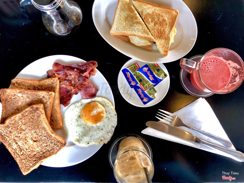 French toast với bacon và trứng ốp la. Sandwich kẹp trứng, sausage. Nước ép dưa hấu và cà phê sữa đá. 
